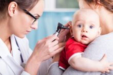 Doctor checking ears of small boy with earache
